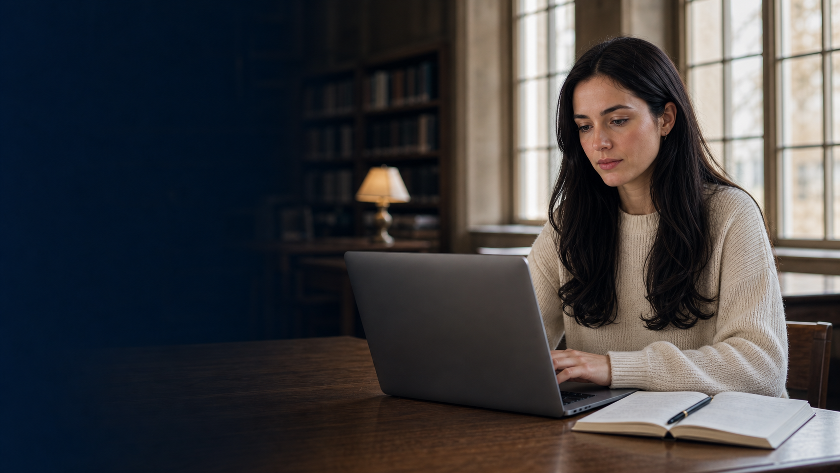 Student with a visible face studying at a laptop in a quiet university library